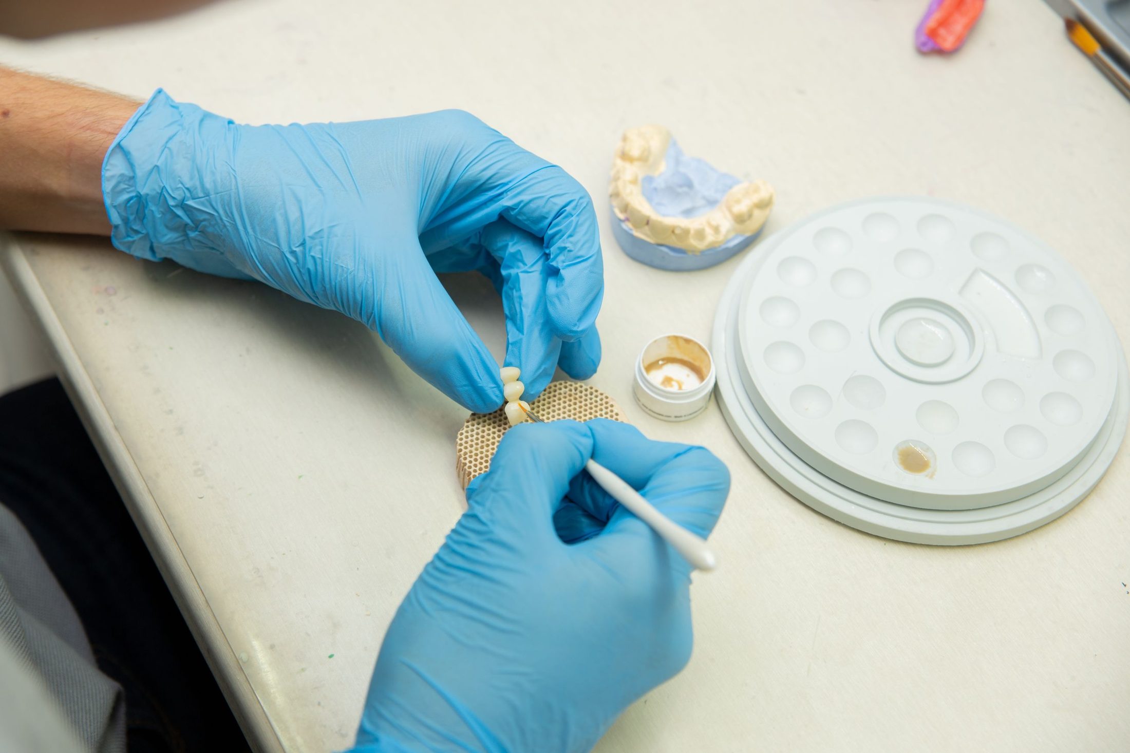 A dental technician finishing a ceramic crown in the lab