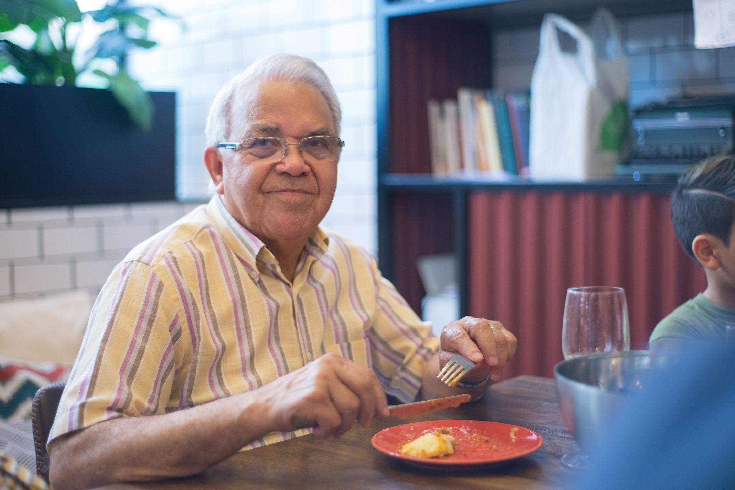 An older man smiling over his meal