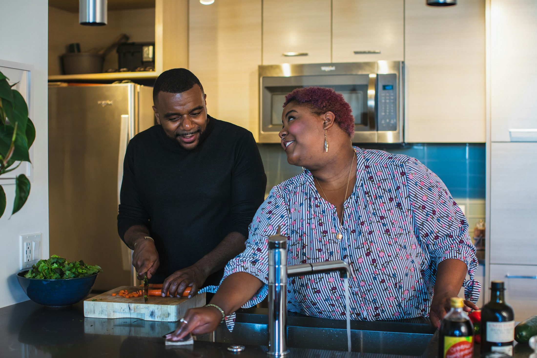 A couple laughing as they cook together at home