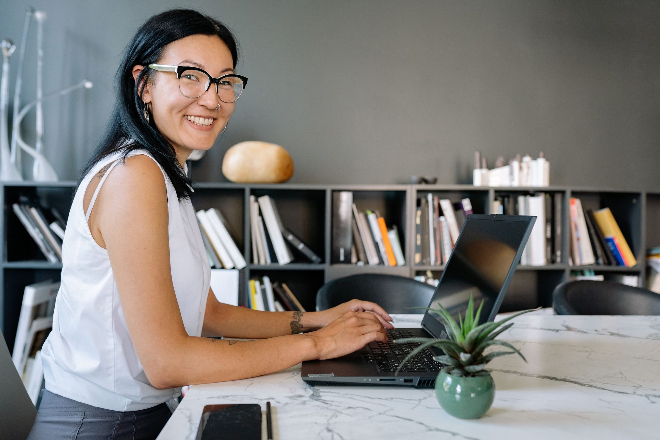 A woman smiling as she fills in a form on her laptop
