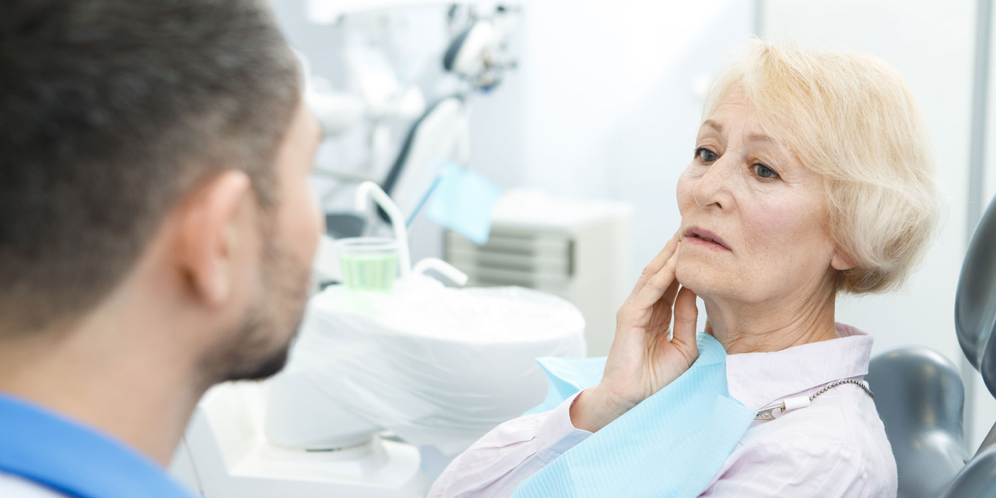 A denture wearer holding her jaw where a loose denture rubs