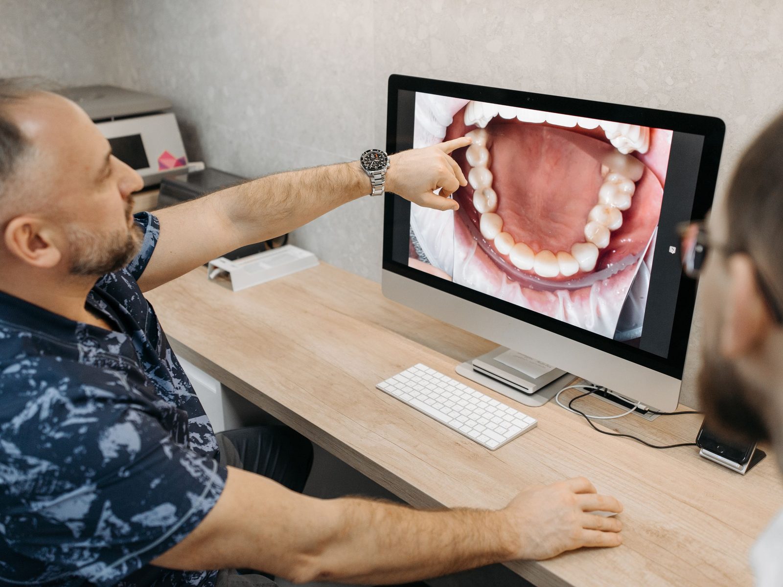 A dentist pointing out an intraoral camera image on a monitor