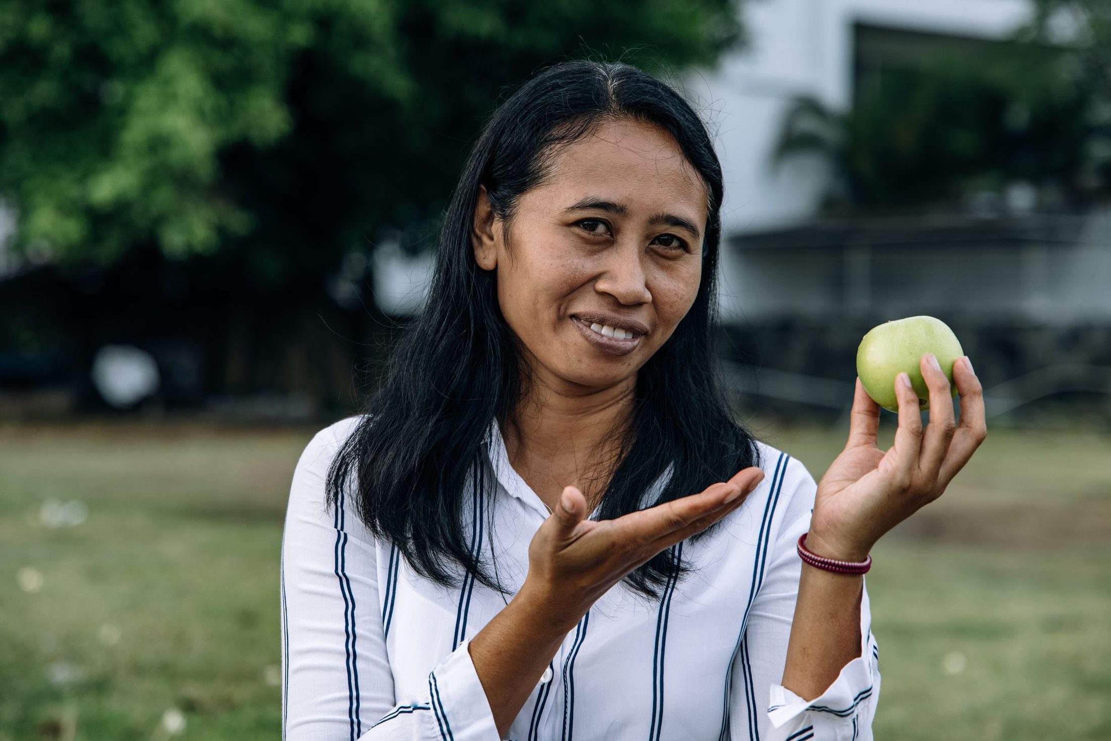 A smiling woman holding a green apple